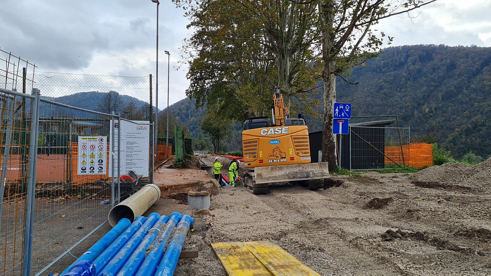 Z GRADBENIMI POSEGI OBČINA TOLMIN UREJA približno 240-metrski odsek ceste ob jugozahodnem robu Brajde, odvodnjavanje meteorne vode z območja športnega parka in vodovodno omrežje.
